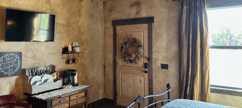 Image of granary room at inn at sunset mill ranch, view out of the window, television, writing desk and coffee station. 