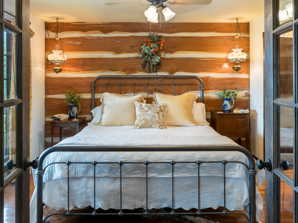 Image of king iron bed with wooden wall at wimberley lodging Inn at Sunset Mill Ranch