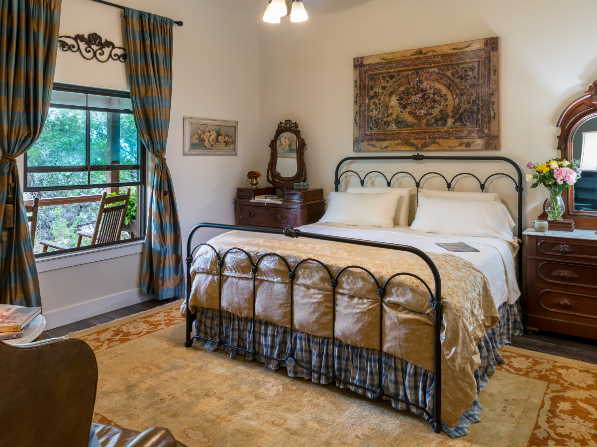 Image of king iron bed with picture window at Inn at Sunset mill Ranch in Wimberley texas