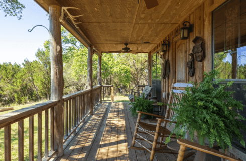 Image of wooded front porch with Southern Rocking Chairs in the Winters Mill Cabin Accommodations at Inn at Sunset Mill Ranch in Wimberley Texas