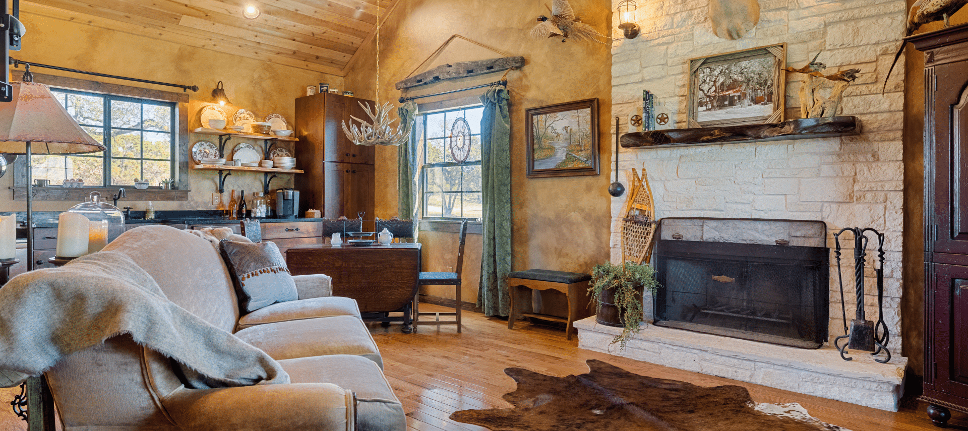 Image of interior shot of fireplace, couch and kitchen of the Winter's Mill Cabin accommodations at Inn at Sunset Mill Ranch in Wimberley Texas