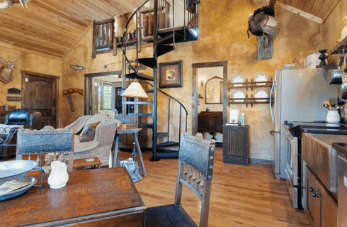Image of Magnolia Home inspired interior of cabin rental with wood dining table and iron spiral staircase in the Winters Mill Cabin Accommodations at Inn at Sunset Mill Ranch in Wimberley Texas